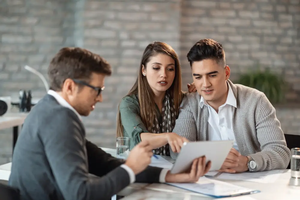 young-couple-using-touchpad-with-insurance-agent-while-making-loan-repayment-plan-meeting